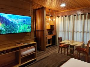 a living room with a television and a dining room at Sonnen Schein Chalés in São Martinho