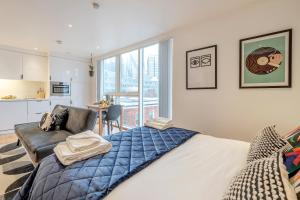 a bedroom with a bed and a couch and a kitchen at Kula London - Tower Hill in London