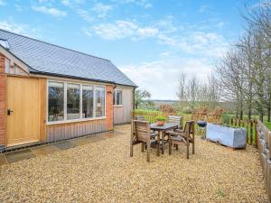 una casa y un patio con mesa y sillas en The Woodshed en Lower Boddington