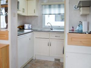 een keuken met witte kasten, een wastafel en een raam bij Paul Jones Bay 26 - Uk46688 in Mainsriddle
