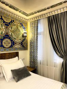a bedroom with a bed and a blue and gold wall at Bobosh Hotel in Bukhara