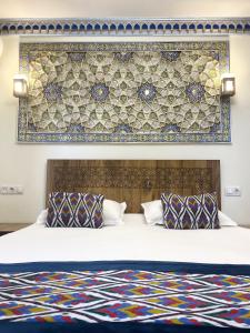a bed with two pillows and a wall with at Bobosh Boutique in Bukhara