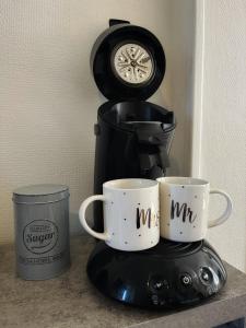 two coffee mugs on a coffee maker with a clock at STUDIO COSY Gare & centre-ville in Saumur +5 photos