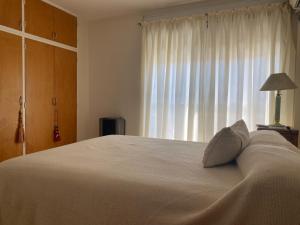 um quarto com uma grande cama branca e uma janela em Cuyen 1 Pleno Centro em Santa Rosa