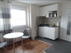 eine kleine Küche mit einem Tisch, einem Tisch und Stühlen in der Unterkunft Kleines Appartement Gut und Preiswert in Stuttgart