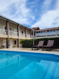 a swimming pool with two benches in front of a building at Pousada Jangadeiro in Porto Seguro