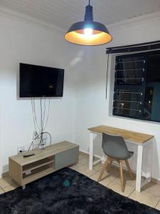 a living room with a desk and a tv and a chair at Rest Easy with 24/7 security in Cape Town