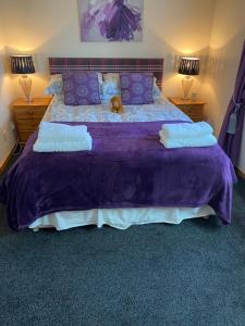 a purple bed with a teddy bear sitting on it at Cameron apartment Loch Ness in Fort Augustus