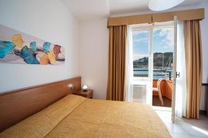 a bedroom with a bed with a view of the ocean at Hotel Belmare in Porto Azzurro