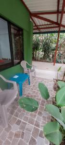 een patio met een tafel en stoelen en een groene muur bij Corcovado & Drake Inn in Drake