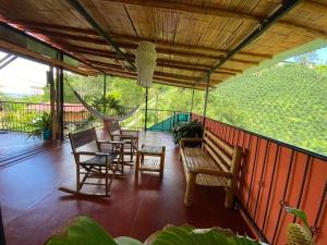 - une terrasse couverte avec des chaises, des tables et un hamac dans l'établissement cabaña de guadua entre montañas, à Palestina