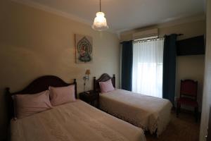um quarto com 2 camas e uma janela em Residencial Miguel José em Estremoz
