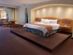um quarto de hotel com uma cama grande e uma mesa em Hotel Mirage - Centro Histórico de Querétaro em Querétaro