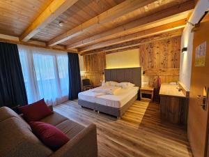 una grande camera da letto con un letto e un divano di Hotel Mirabel a San Vigilio Di Marebbe