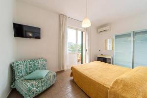 a bedroom with a bed and a chair and a television at Hotel Belmare in Porto Azzurro