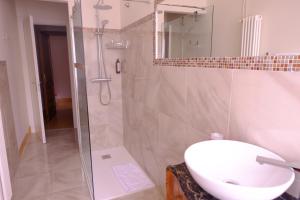 La salle de bains est pourvue d'un lavabo blanc et d'une douche. dans l'établissement Bed & Breakfast Costanza4, à Scanno