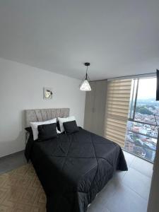 a bedroom with a black bed and a large window at apto piedra pintada alta in Vallecito