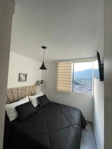a bedroom with a black bed and a window at apto piedra pintada alta in Vallecito