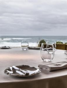 a table with two glasses and a plate on the beach at As Garzas in Barizo