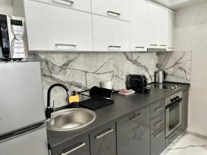 a kitchen with white cabinets and a sink at LT Apartment in Vratsa