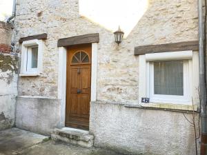 a stone building with a wooden door and two windows at Cocon chaleureux entièrement renové à 150m de le Seine in Saint-Mammès