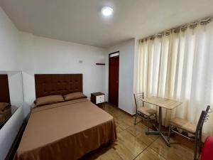 a bedroom with a bed and a desk and a table at Hospedaje Senegal cerca al aeropuerto in Lima