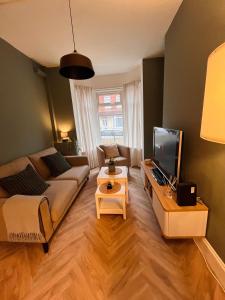 a living room with a couch and a tv at Kings Bridge Townhouse in Belfast