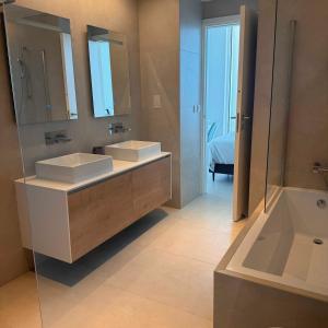 a bathroom with two sinks and a mirror and a tub at Ayia Napa Marina Exclusive Apartment in Ayia Napa