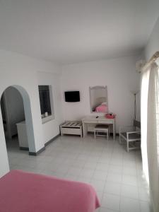 Habitación blanca con cama y TV en El Sol Hotel en Kapsálion