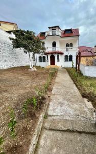 uma casa branca com uma porta vermelha e uma entrada em Vila Taga Guesthouse em Krujë