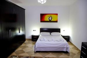 um quarto com uma cama com lençóis brancos e almofadas em Vila Taga Guesthouse em Krujë