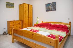 a bedroom with a wooden bed with red pillows at Biró apartmanház Sármellék in Sármellék