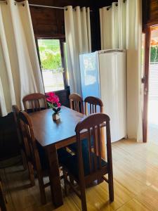 uma mesa de jantar com cadeiras e um frigorífico em Chalé Vila das Oliveiras em Penha