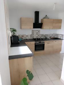 a kitchen with wooden cabinets and a white tile floor at Agréable pavillon in Nailloux