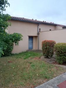 a house with a blue door and a yard at Agréable pavillon in Nailloux