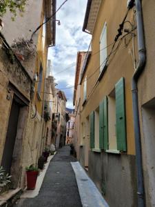 a narrow alley with green shutters on a building at Maison In Vino in Nyons