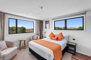 a bedroom with a bed and a chair and two windows at Golden Hotel in Christchurch