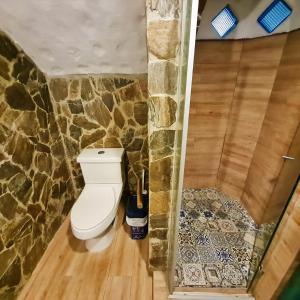 a bathroom with a toilet and a stone wall at CHEVERE BEACH CABAÑAS SAS in Puebloviejo