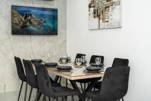 a dining room table with black chairs and a painting at Spiros Luxury Apartments in Ayia Napa