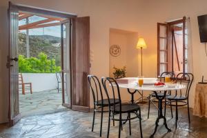 ein Esszimmer mit einem Tisch und Stühlen sowie Aussicht in der Unterkunft Aegean Cottage Andros in Makrotándalon