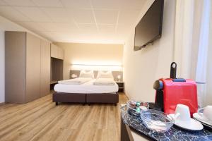 a hotel room with a bed and a red suitcase at Hotel am Kreisel Self-Check-In by Smart Hotels in Lachen