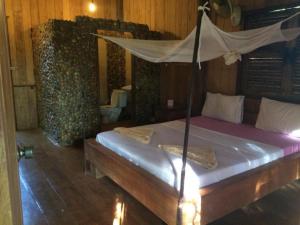 1 dormitorio con 1 cama con dosel en Tree Top Eco-Lodge, en Banlung