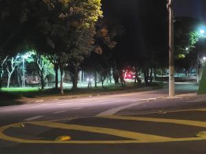 une rue vide la nuit avec une flèche jaune sur la route dans l'établissement Suíte Proença, à Campinas