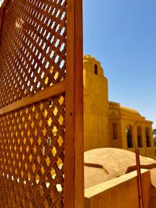 ein Holzzaun mit einem Gebäude im Hintergrund in der Unterkunft Jewel Howard Carter Hotel in Luxor