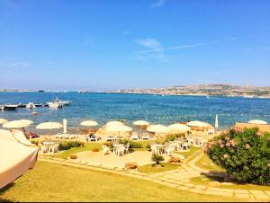 - une vue sur une plage avec des parasols et l'océan dans l'établissement Incantevole Casa Vacanze MIMOSA La Maddalena, à La Maddalena