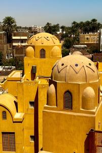 ein gelbes Gebäude mit Kuppeln darüber in der Unterkunft Jewel Howard Carter Hotel in Luxor