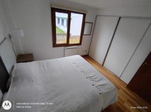 a bedroom with a white bed and a window at Mirando al Sol Ushuaia in Ushuaia