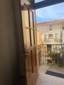 une porte donnant sur un balcon avec vue sur un bâtiment dans l'établissement Comfortable Gite (3) in attractive Languedoc village, à Magalas