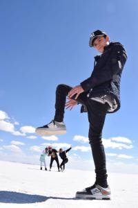 a young boy standing in the snow with his foot in the air at Hostal Beds of salt Ga in Uyuni