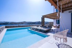 eine Villa mit einem Pool und einer Terrasse mit Stühlen in der Unterkunft Myko Grand Villa by Bestofmikonos in Ftelia
